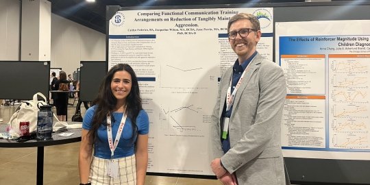 Photo of Caitlyn Ziolkowski and Dr. Cody Morris smiling in front of a poster with Caitlyn's research