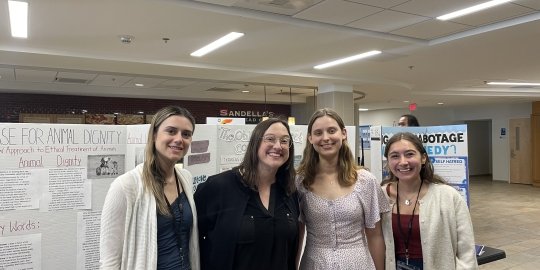 Group photo of students and professor in front of posterboard.