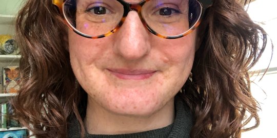 Headshot of Mary in glasses and turtleneck.