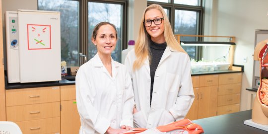 Curesky and student in the lab with their lab coats on