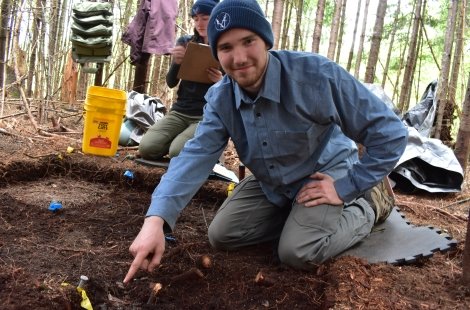 student pointing at something in dig site