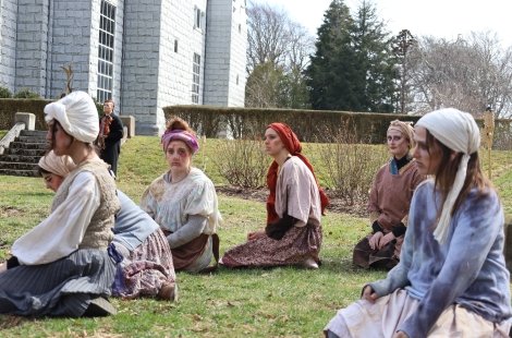 A group of women kneeling on the ground, mourning in Trojan Women