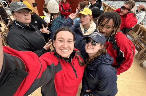 Smiling students take a group selfie aboard a ship