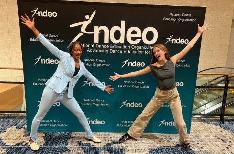 Students pose in front of welcome poster at dance education conference