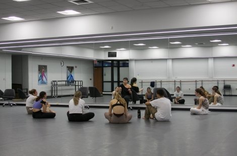 Students sit on the studio floor and learn from a guest artist