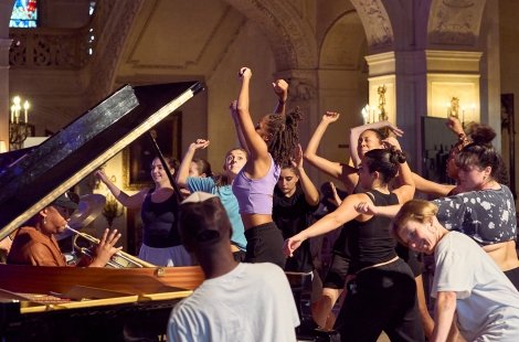 Students dancing around a grand piano
