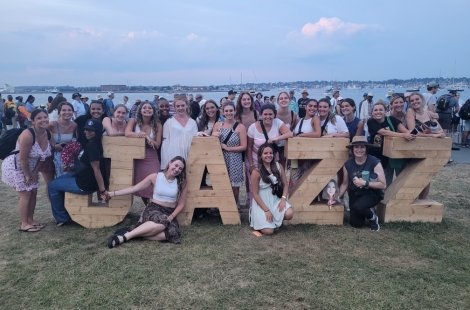 Dance students grouped around a wooden sculpture spelling JAZZ