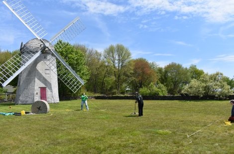 Students surveying a grassy field near a windmill