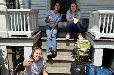 three female students sharing lunch on porch steps