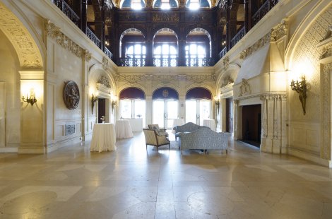 A three-story great hall with a marble fireplace on one side.