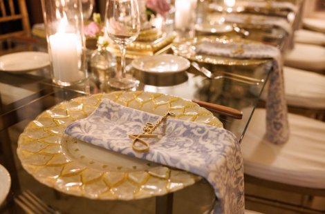 An elegant place setting with a gold plate and embroidered napkin.