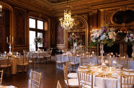A group of tables set for a wedding reception with tall floral centerpieces.