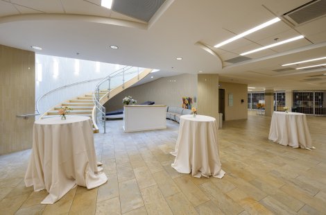 A large, modern lobby area set with high-top cocktail tables covered in white linens.