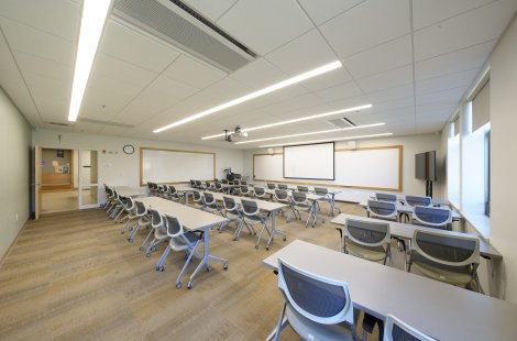 A large classroom with rows of tables and chairs.