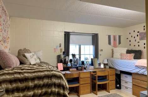 A shared room with two raised beds, rugs on the floor and decorations on the walls.