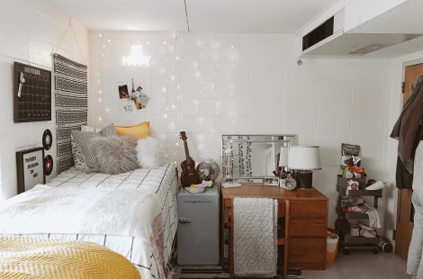 A dorm room with a raised bed, a rug on the floor and decorations on the walls.