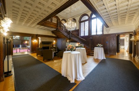 A large lobby area with cocktail tables and a high, ornate ceiling.