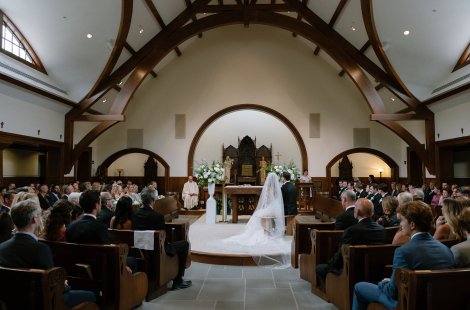 A bride and groom sit near the altar during a wedding ceremony in a church.