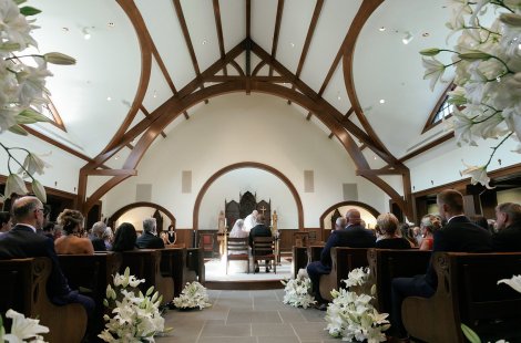 A bride and groom sit near the altar during a wedding ceremony in a church.