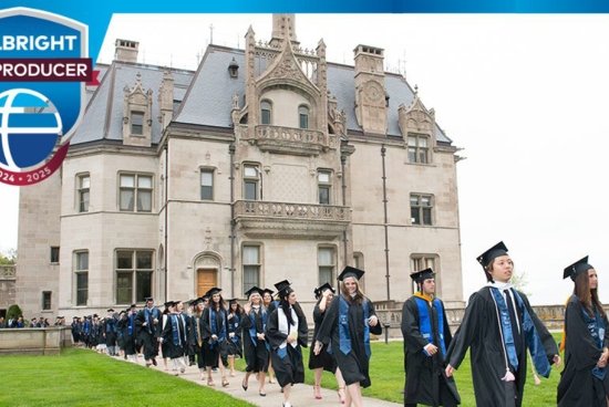 A line of people in graduation gowns walking down a sidewalk