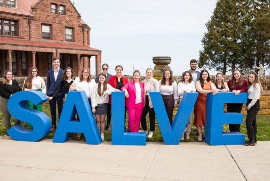A group of people standing behind blue letters that spell out Salve