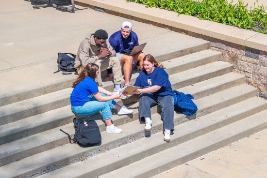 A group of students studying on the back steps of O'Hare.
