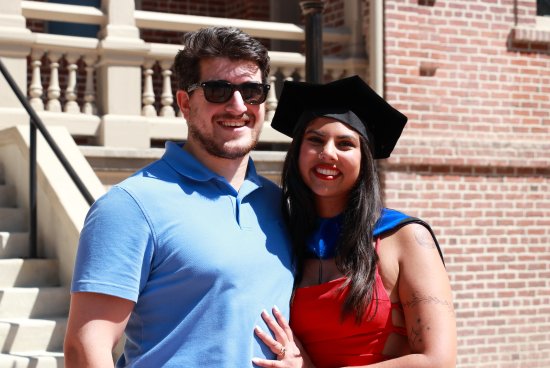 Natalie Buddiga poses with her husband in doctoral regalia at graduation.
