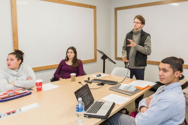 students sitting around table listening to presentation