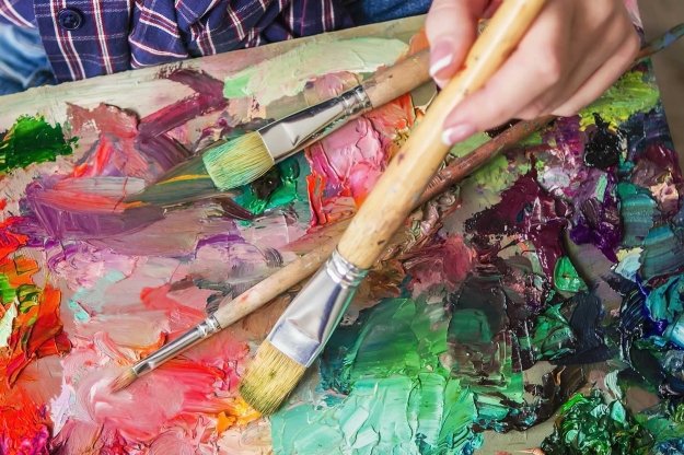 Paintbrushes and different paint colors on a canvas