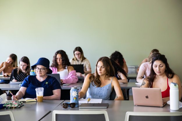 A group of MFA students sitting in a classroom participating in a residency writing workshop.