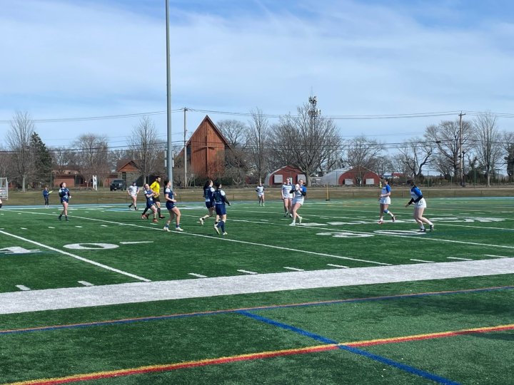 Women playing rugby on an athletic field