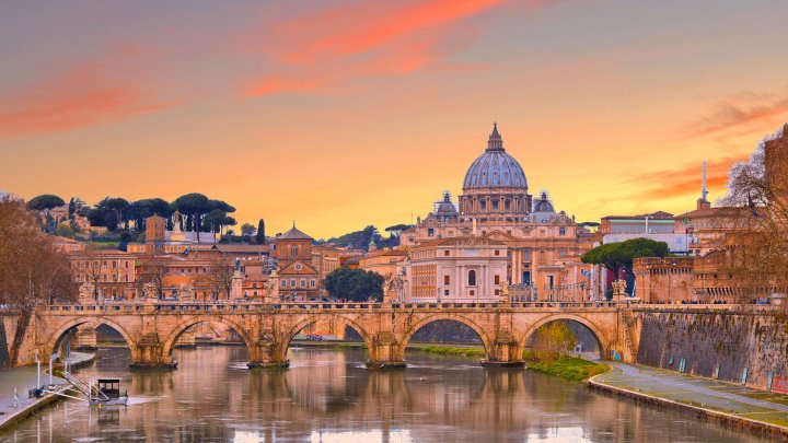 Roman buildings and arches over a waterway against a golden sky