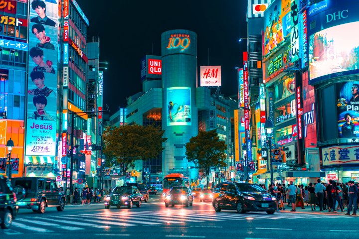 nighttime Tokyo city street corner brightly lit with neon signs