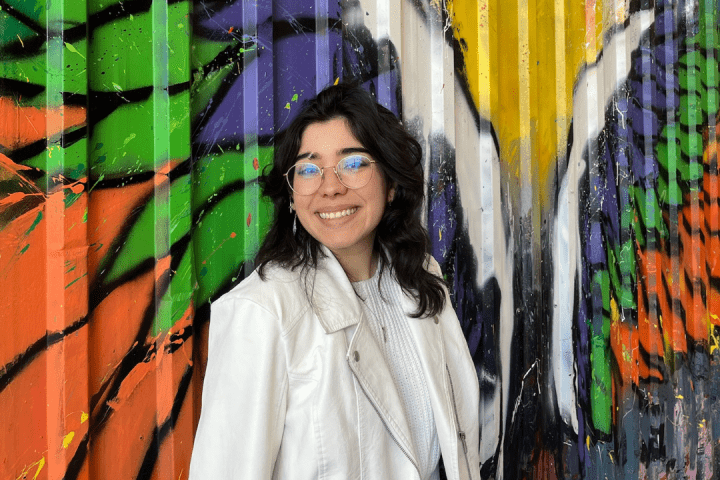 Maria Barragan in front of a brightly painted mural