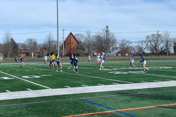 Women playing rugby on an athletic field
