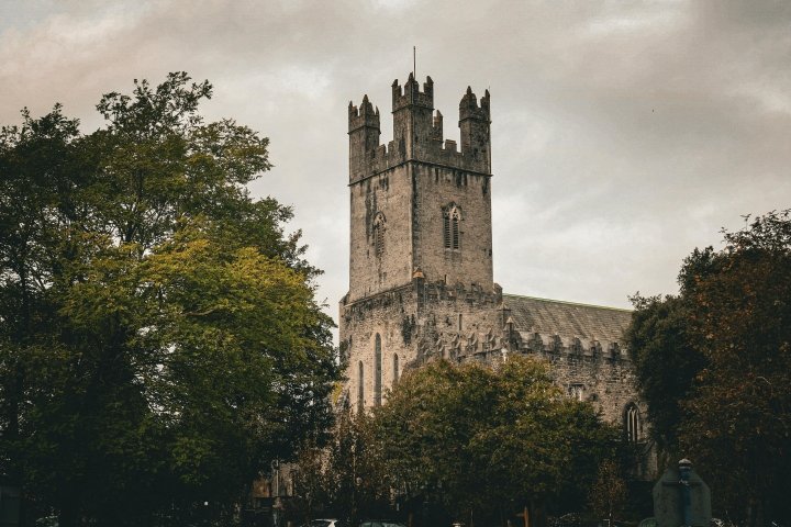 Irish castle behind leafy trees against a gloomy sky
