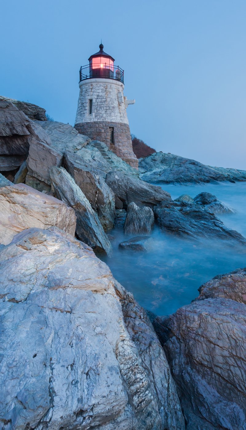 A rocky coastline with a lighthouse in the background.