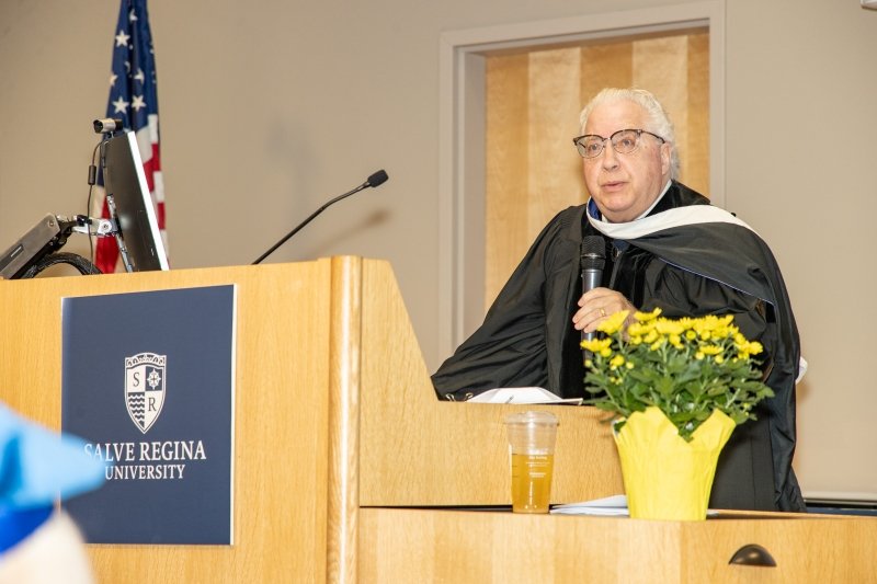 Sacco in regalia speaking at a Salve Regina University podium.