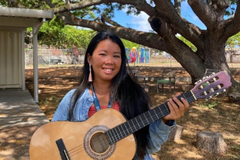 Joy Pye smiling holding a guitar