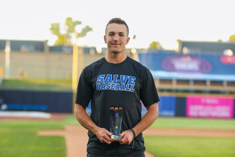 Brandon Grover standing on the baseball field holding a trophy