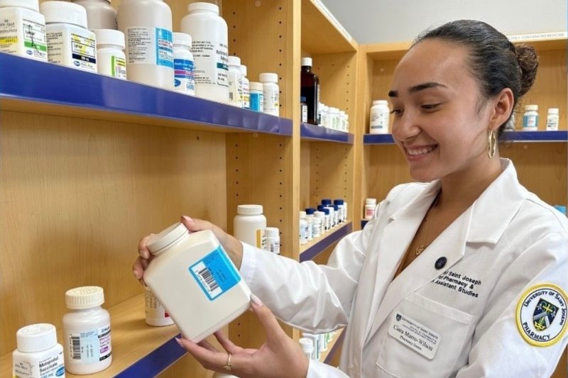 Marro-Wilson in white lab coat looking at a pill bottle.