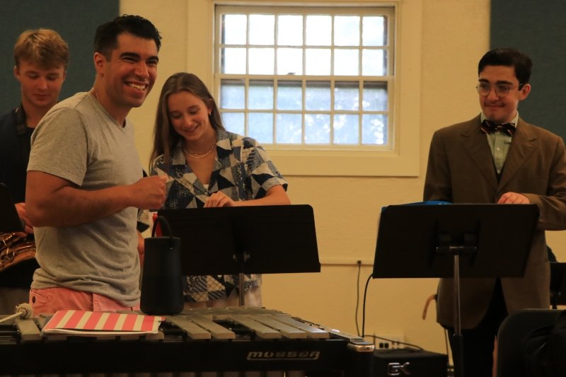Students smiling in a music room behind their music stands.