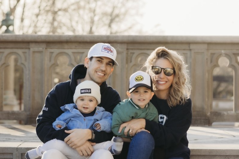 A family photo sitting on steps with John, Sarah and their two kids on their laps.