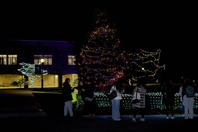 photo of tree light up for christmas outside with students gathered near.