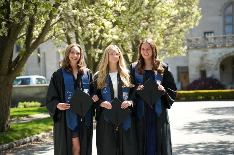 Group photo of the three valedictorians in their regalia outside of Ochre Court