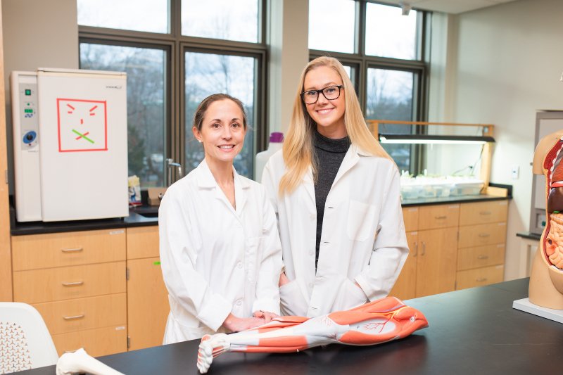 Curesky and student in the lab with their lab coats on
