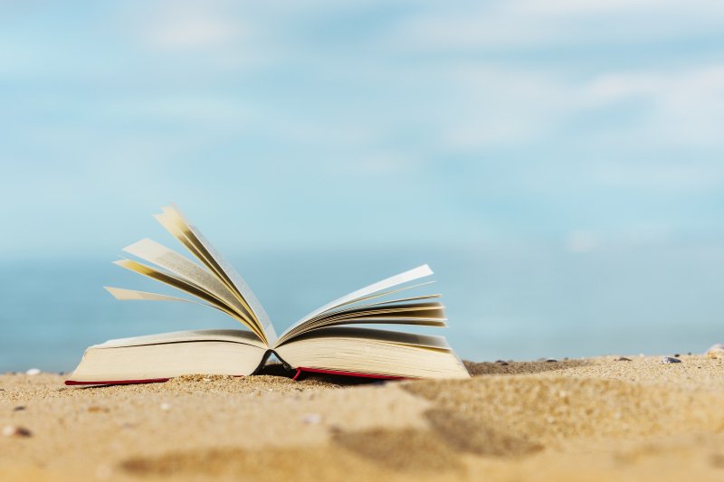Book laying on the sand at the beach.