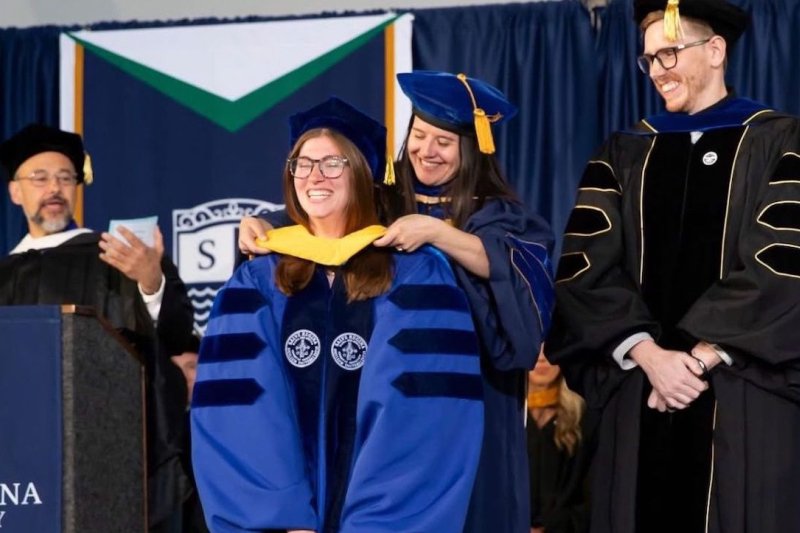 Ph.D. graduate getting academic regalia at commencement