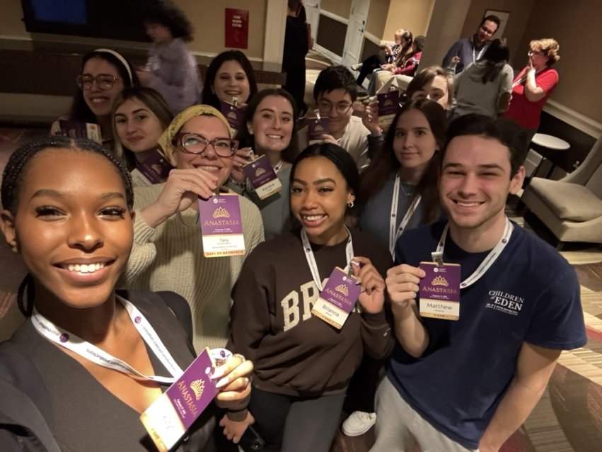 Students smiling with their "Anastasia" IDs in group selfie.