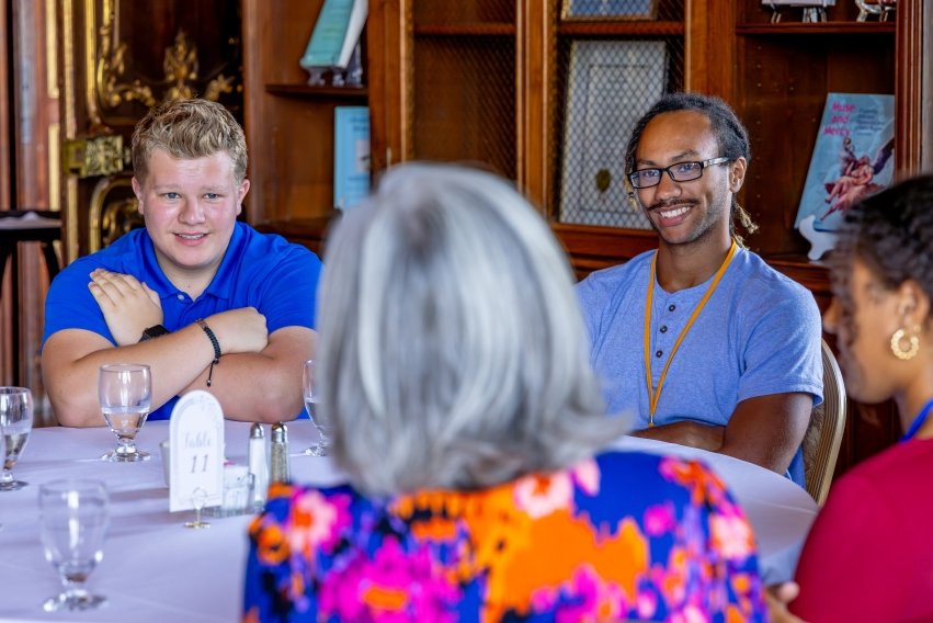 Two students engaging with others at table at compass lunch